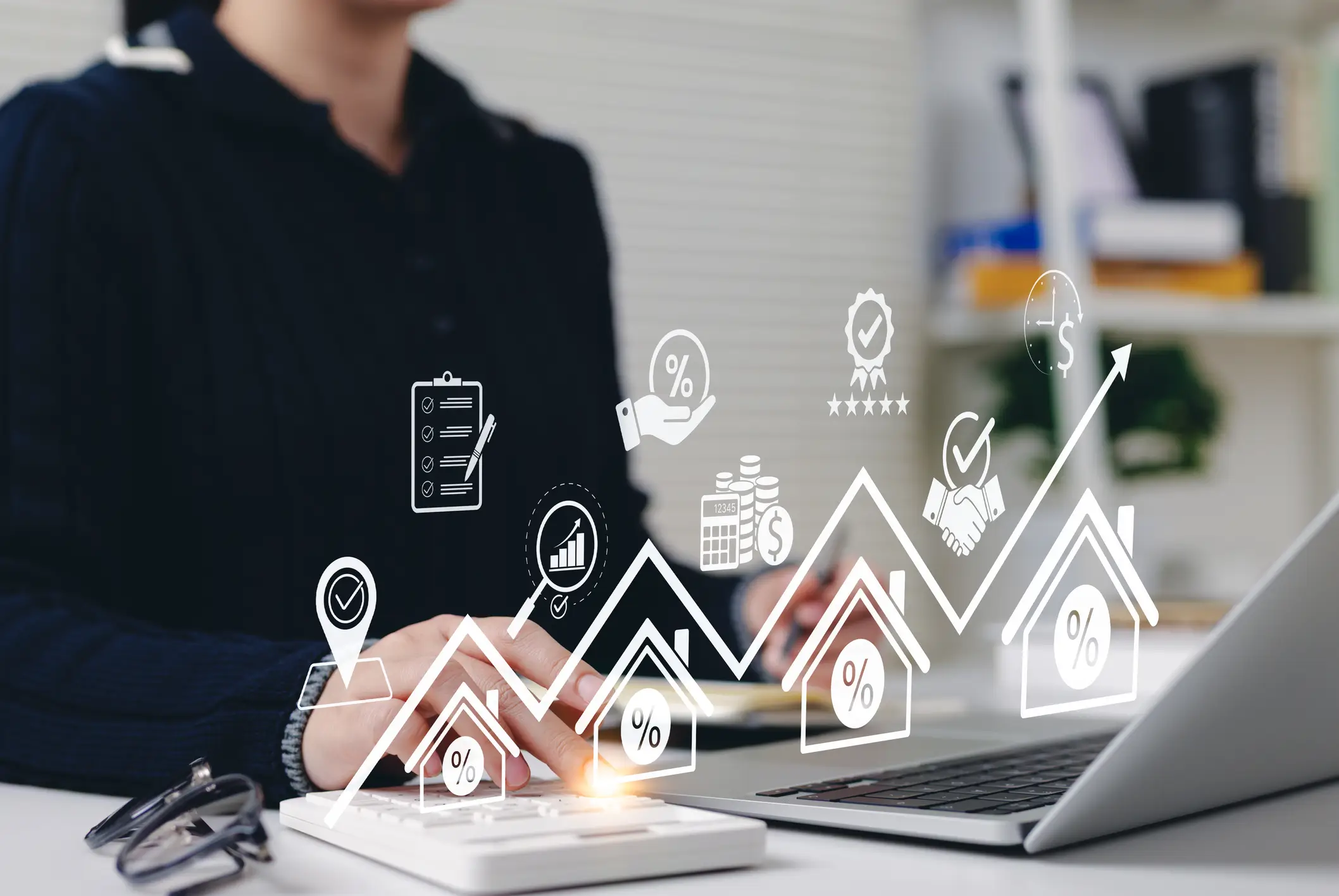 Person working on laptop with digital finance icons floating above.