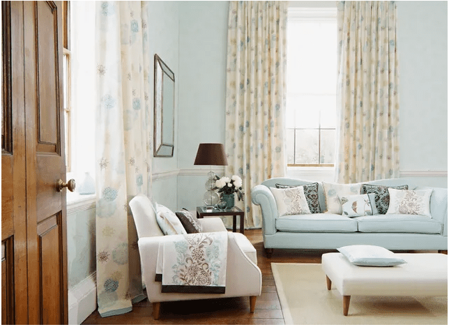 Cozy living room with floral curtains and soft blue sofa.