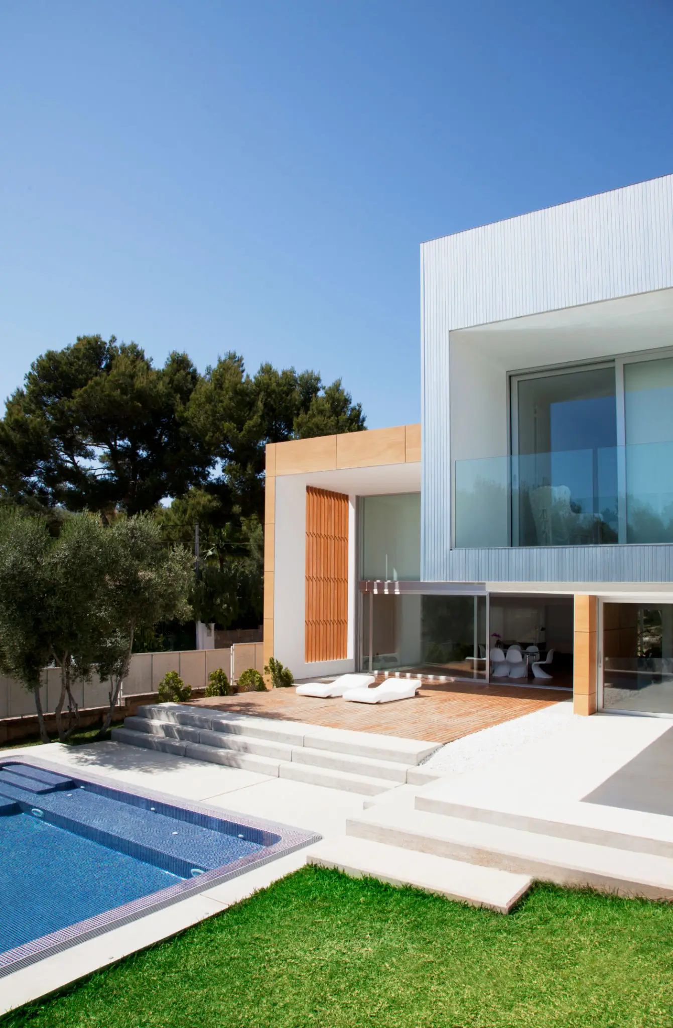 Modern white house with glass balcony and pool.